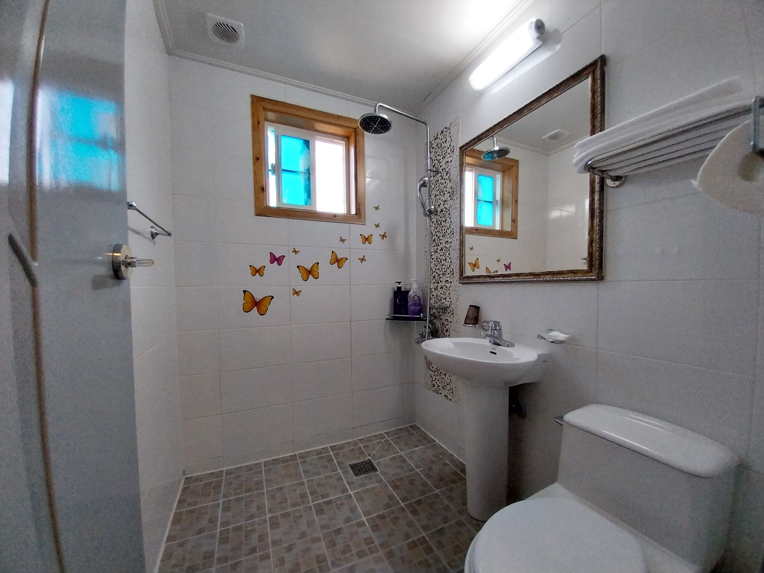 A bathroom with a shower, sink, toilet, and decorative butterfly wall decals.