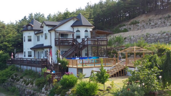Una casa grande de varios pisos con un balcón y una terraza de madera.
