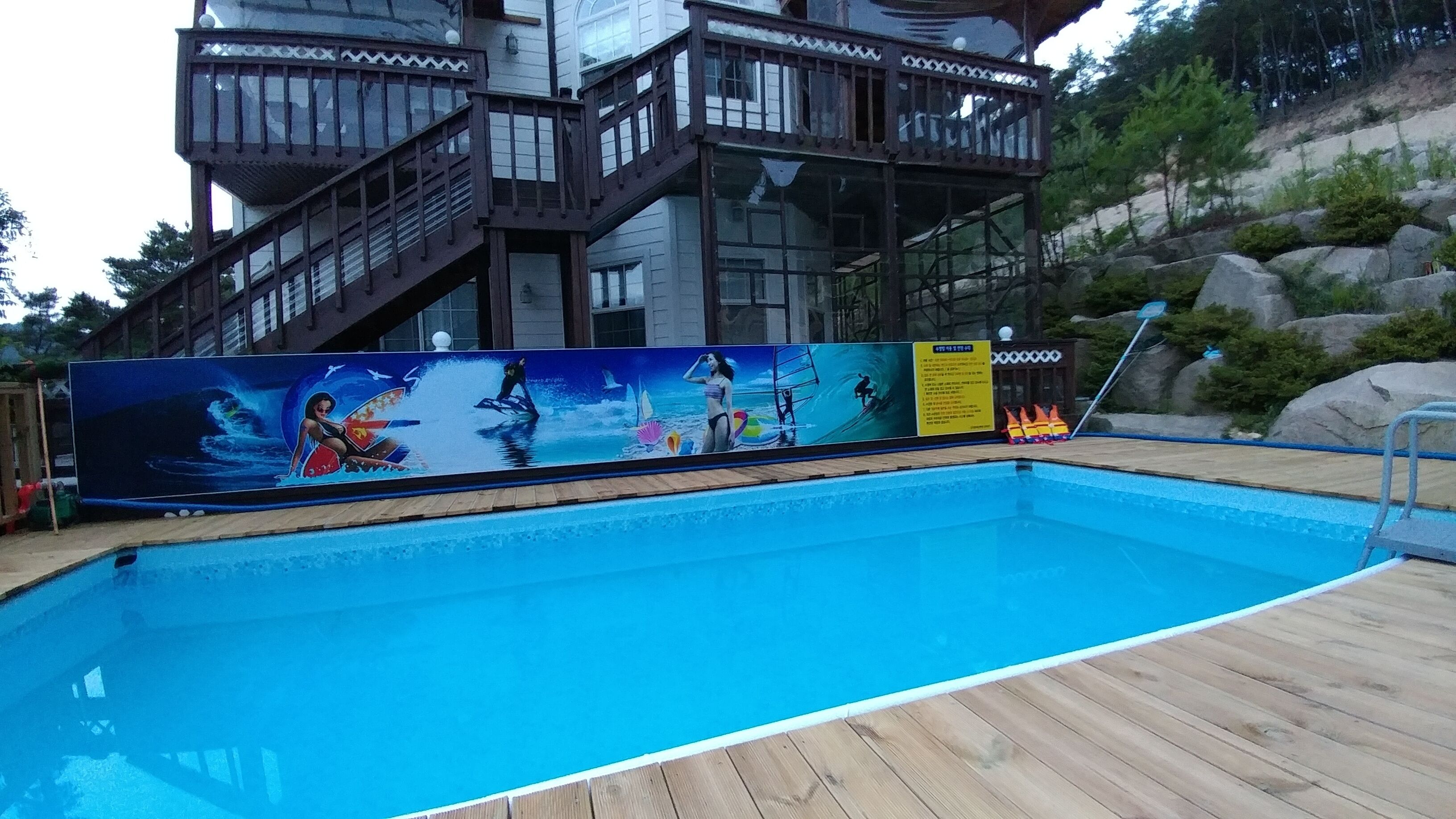 A swimming pool with a wooden deck and a mural depicting underwater scenes.