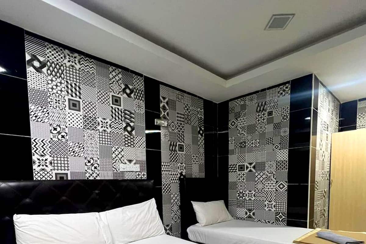 Habitación de hotel con dos camas, un papel tapiz estampado y un espejo.