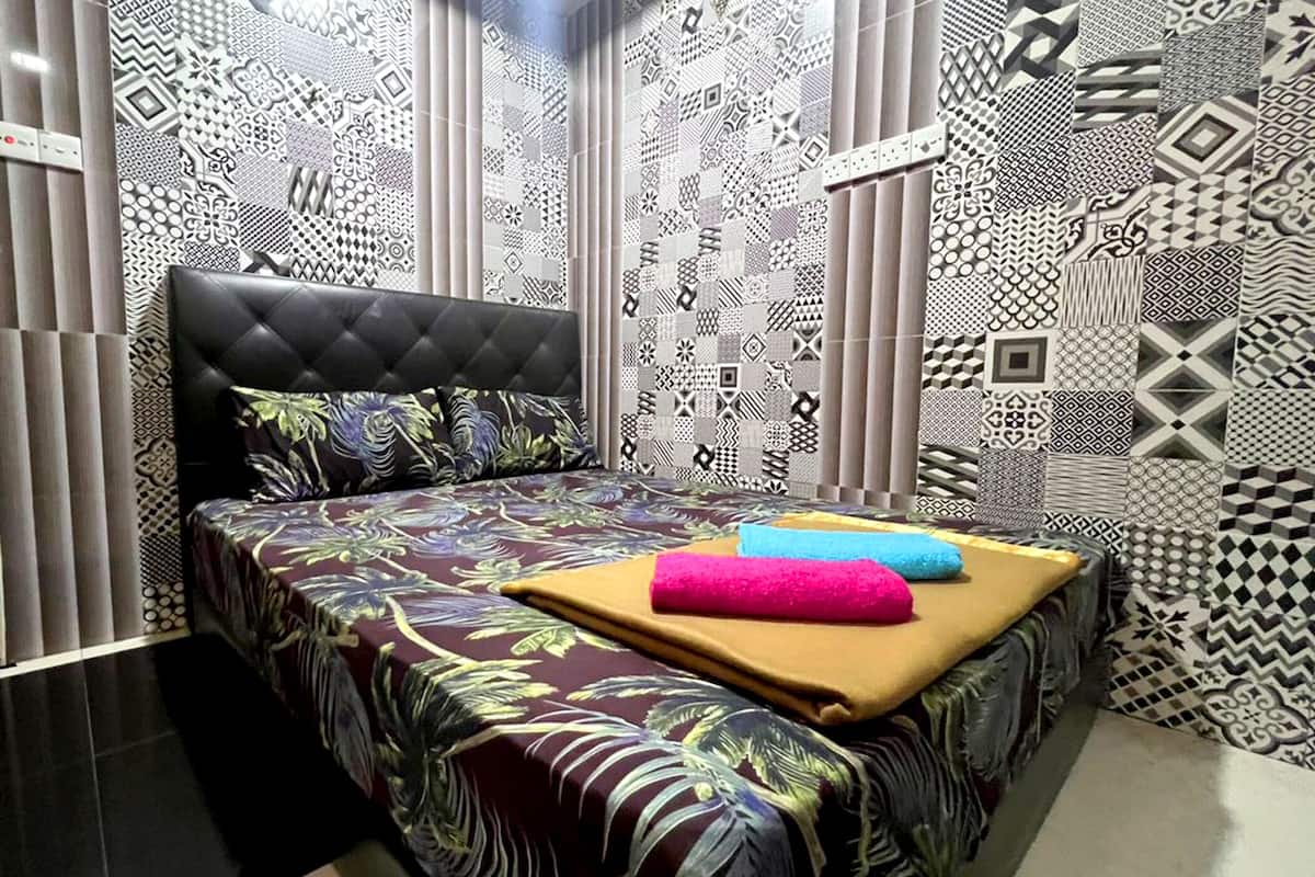 Un dormitorio con cabecera capitonada, ropa de cama estampada con motivos florales y diversos diseños geométricos en las paredes.