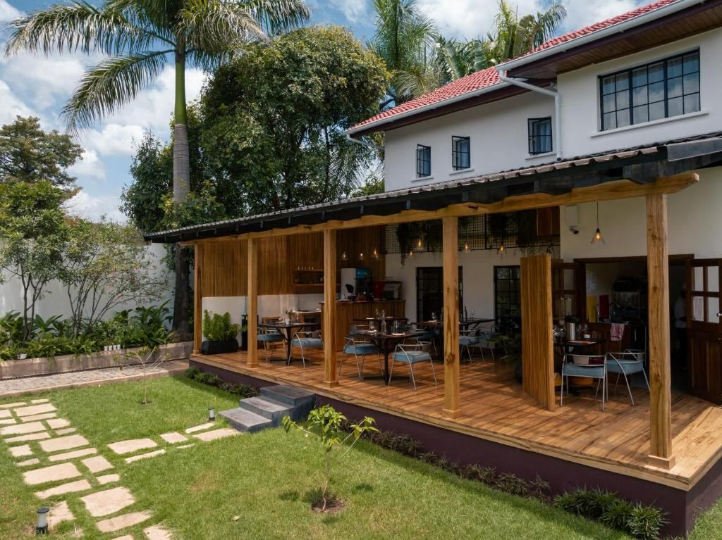 Una casa moderna con un patio cubierto, un sendero de piedra y abundante vegetación.
