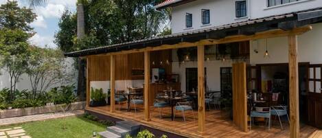 Una casa moderna con un patio cubierto, un sendero de piedra y abundante vegetación.