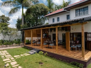 A modern house with a covered patio area, a stone pathway, and lush greenery. - Brubru Lodge  (Moshi)