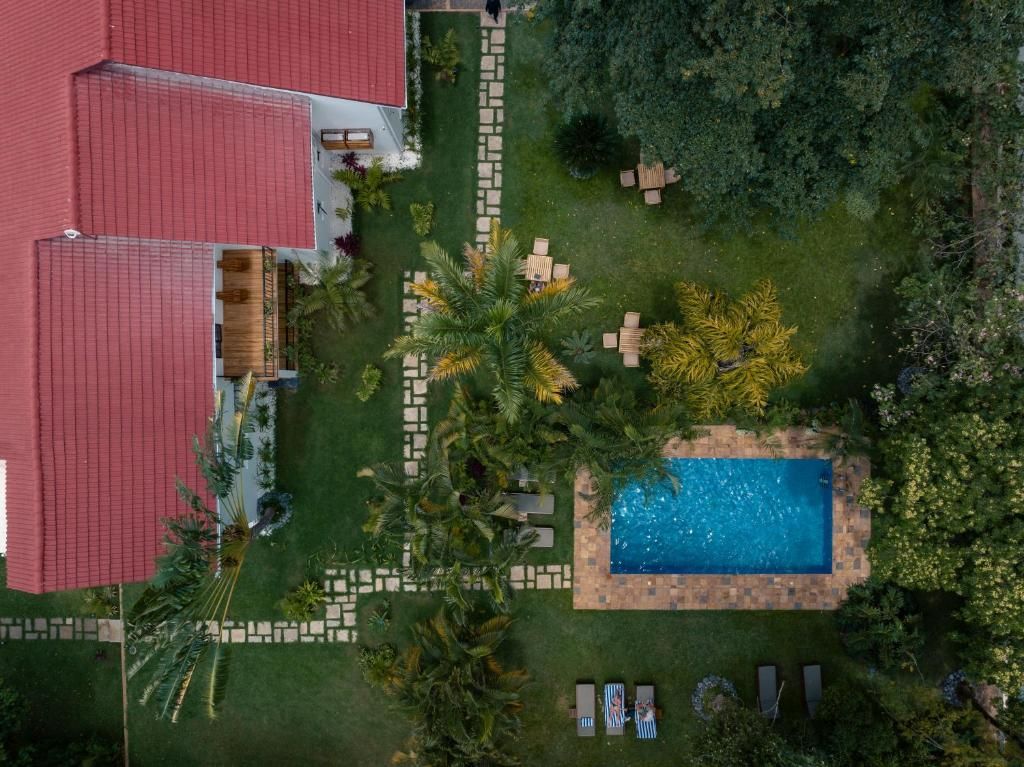 A residential property with a swimming pool, outdoor seating, and a red-roofed building.