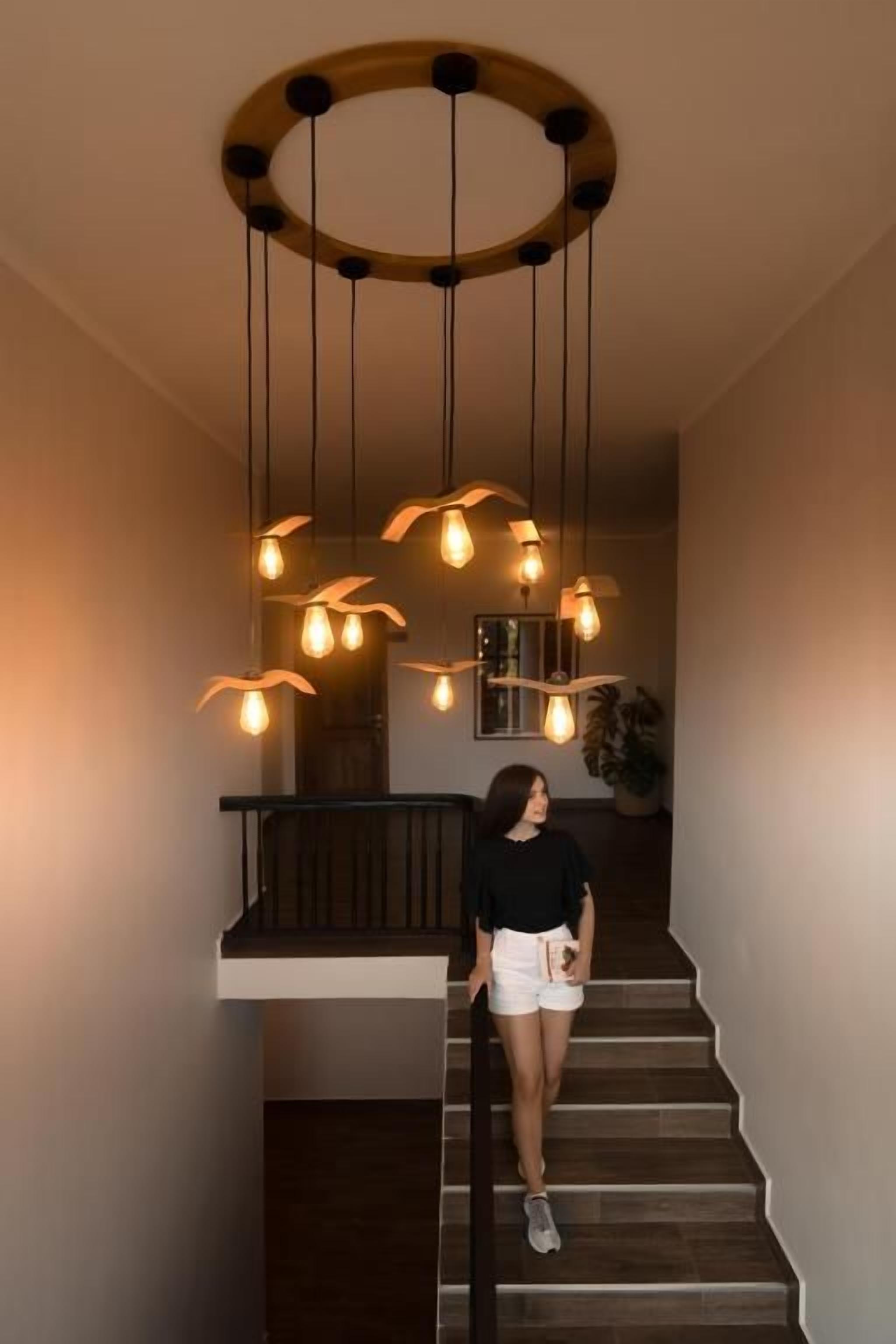 Una escalera con una lámpara de madera circular en el techo y bombillas colgantes.