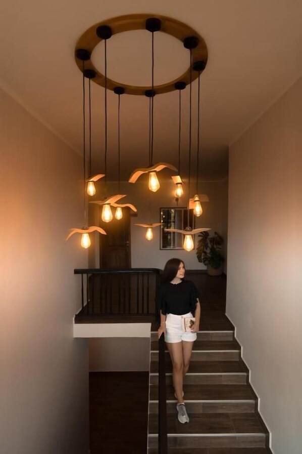 A staircase with a circular wooden ceiling light fixture and hanging bulbs.