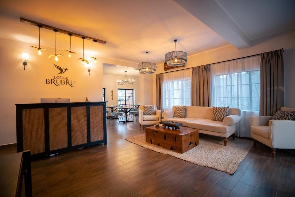 Un hall d’hôtel moderne avec un comptoir d’accueil, un espace salon et un lustre.