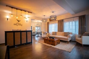 A modern hotel lobby with a reception desk, seating area, and a chandelier. - Brubru Lodge  (Moshi)