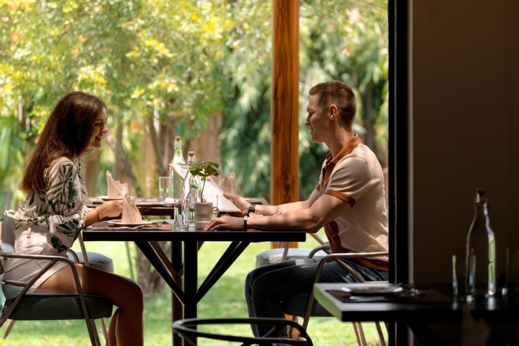 Duas pessoas sentadas à mesa com vista para um jardim.
