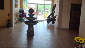 A spacious lobby with a fountain, a large window, and a door leading outside. - Changthai Comfort Guest House (Udon Thani)