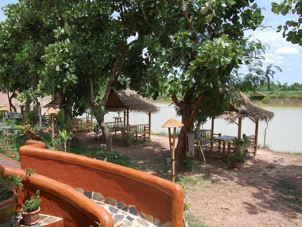 Zona ribereña con cabañas de techo de paja y un muro de piedra.