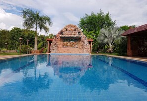 A swimming pool with a decorative stone archway and palm trees in the background.