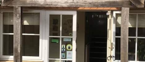 A wooden building with a gabled roof and a set of double doors leading into a staircase.
