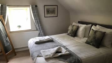 Une chambre à coucher avec un lit, une fenêtre avec des rideaux, un radiateur et un tableau encadré au mur.