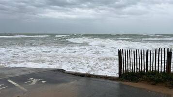 A beach with rough waves and a wooden fence in the foreground.
