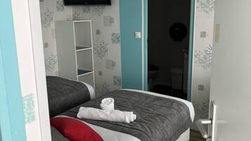 Un dormitorio con cama, televisor y puerta que da a otra habitación.