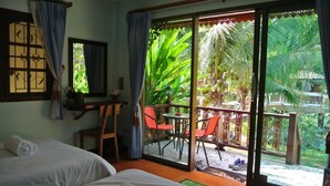 A room with two beds, a desk, and a balcony with chairs and a table. - Himawari Restaurant & Cottage (Khon Kaen)