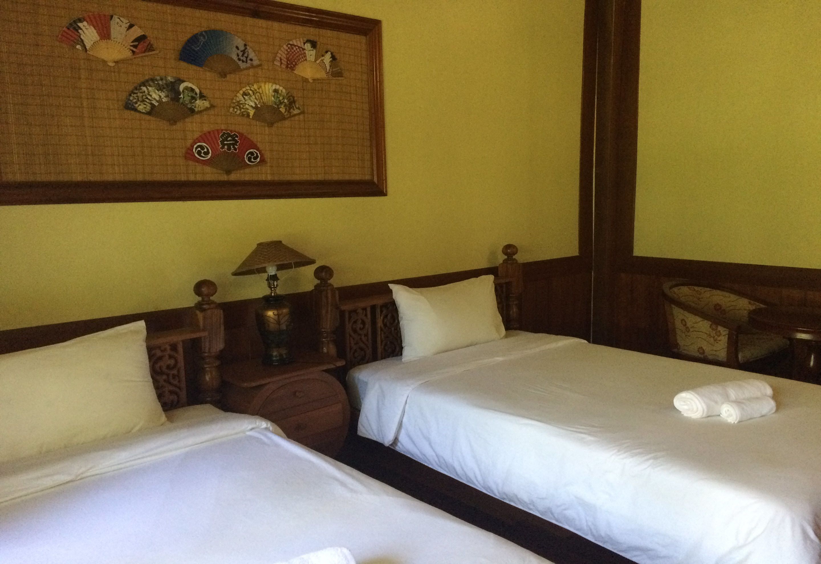 Une chambre d’hôtel avec deux lits, une table de chevet avec une lampe et un élément décoratif fixé au mur.