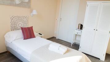 Een slaapkamer met een bed, nachtkastje, kledingkast en een wandairconditioner.