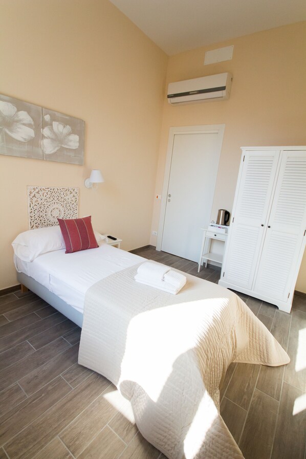 A bedroom with a bed, a nightstand, a wardrobe, and a wall-mounted air conditioner.
