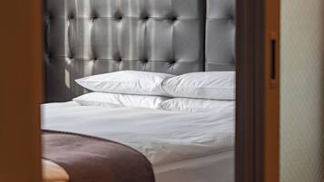 A neatly made bed with white linens and a tufted headboard.