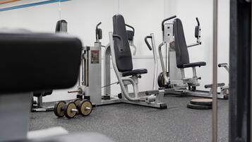 Uma academia com equipamentos de ginástica, incluindo aparelhos de musculação e halteres.