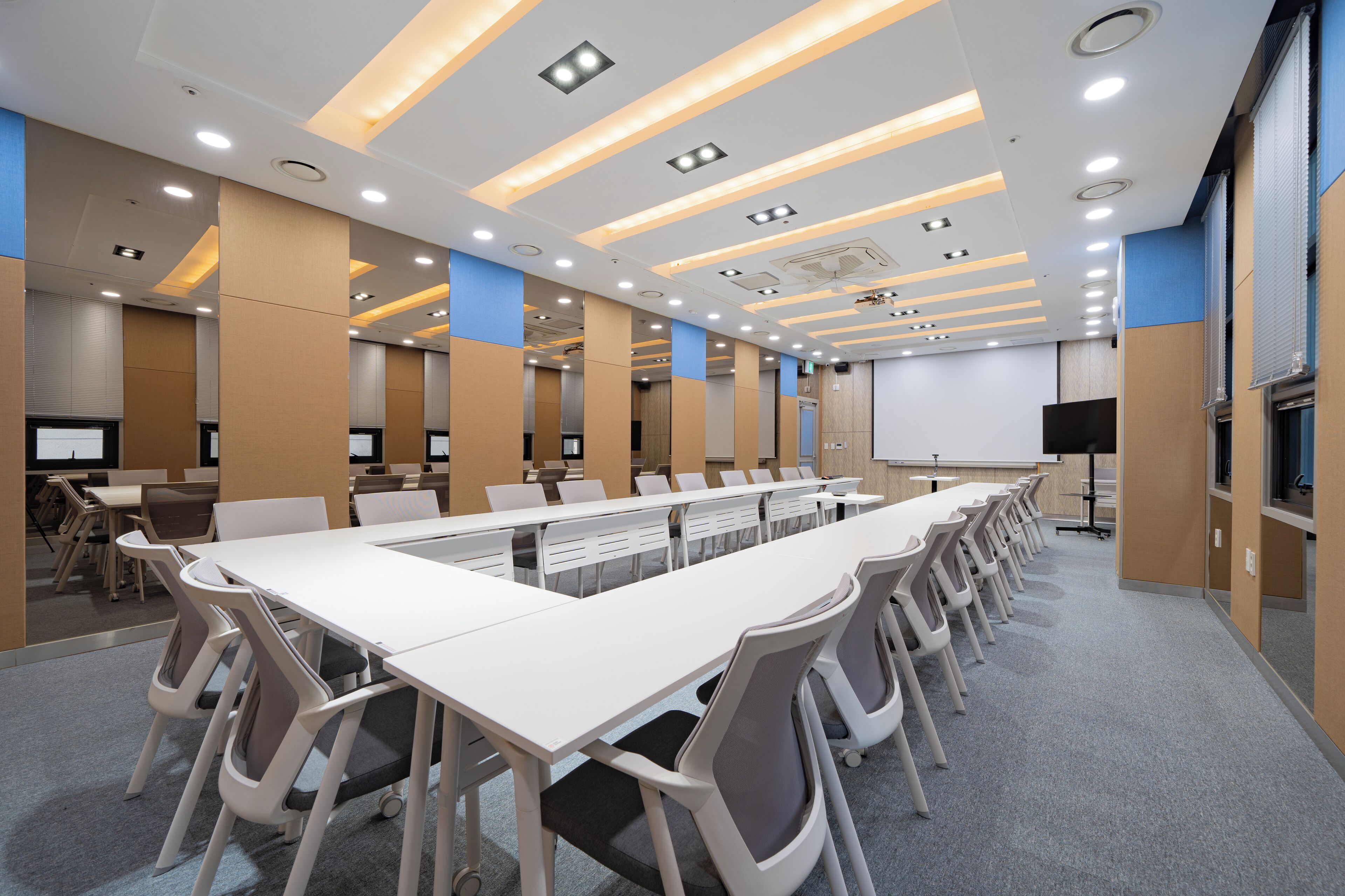 A conference room with a long table, chairs, and a projector screen.