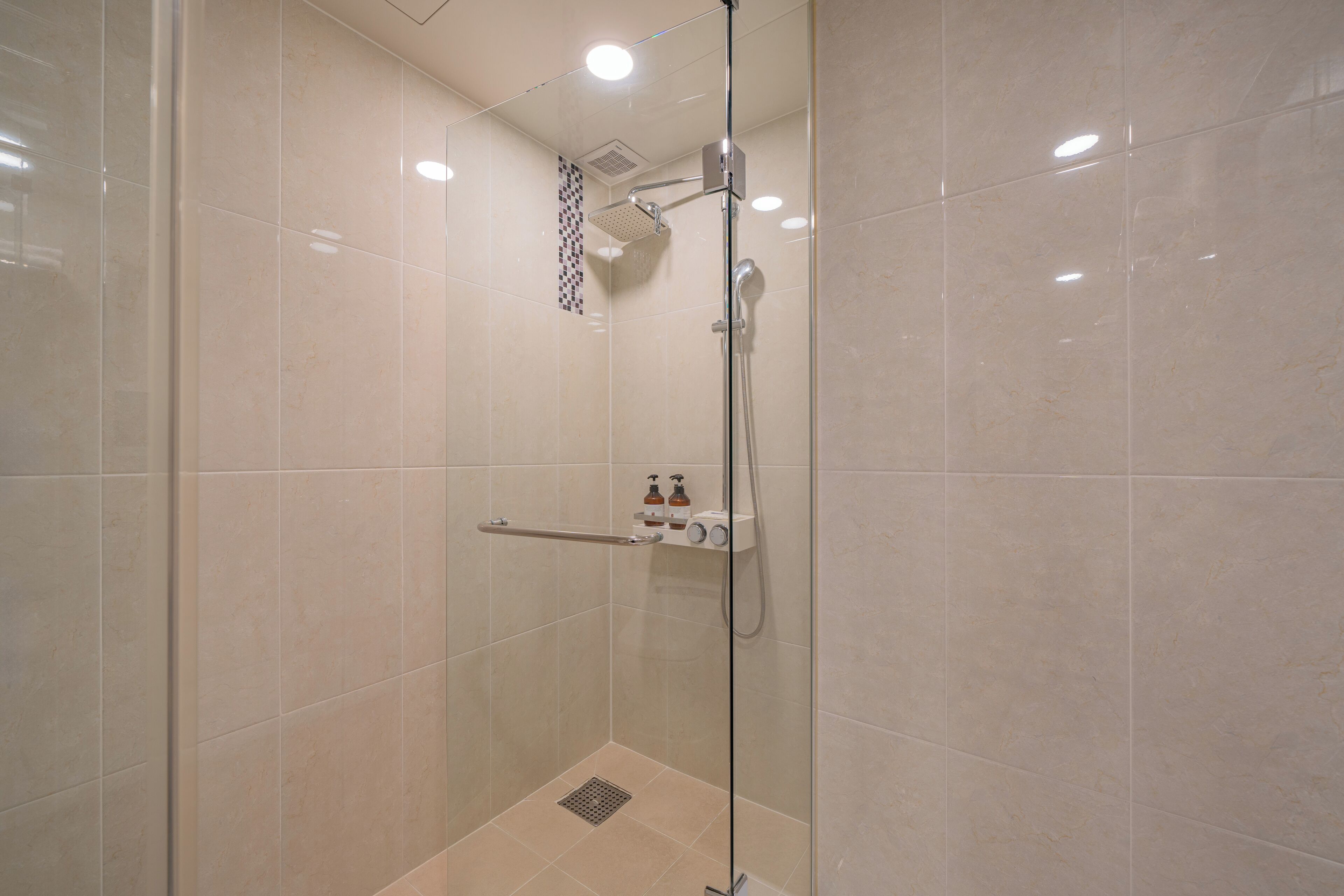 Eine moderne Dusche mit Glastür, Handbrause und einer fest montierten Bedienkonsole.