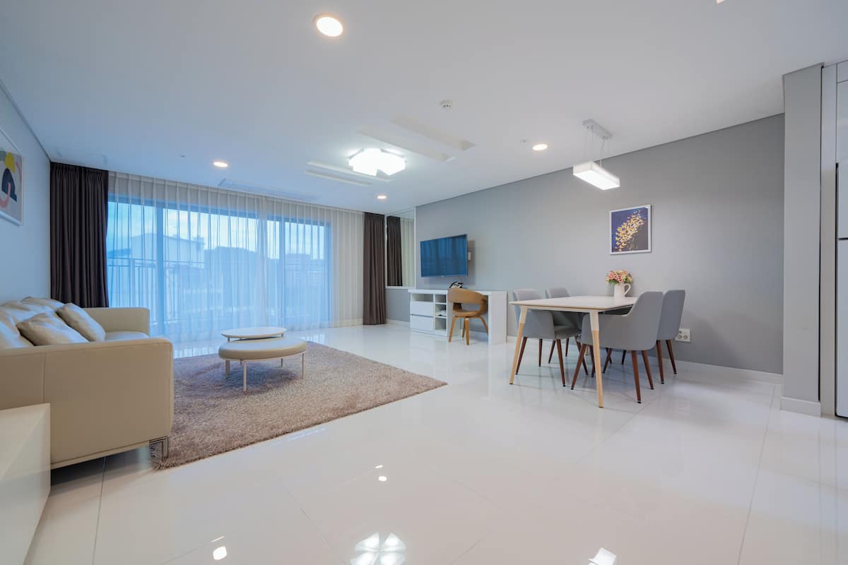Uma sala de estar moderna com sofá, mesa de centro e área de jantar com cadeiras e mesa.