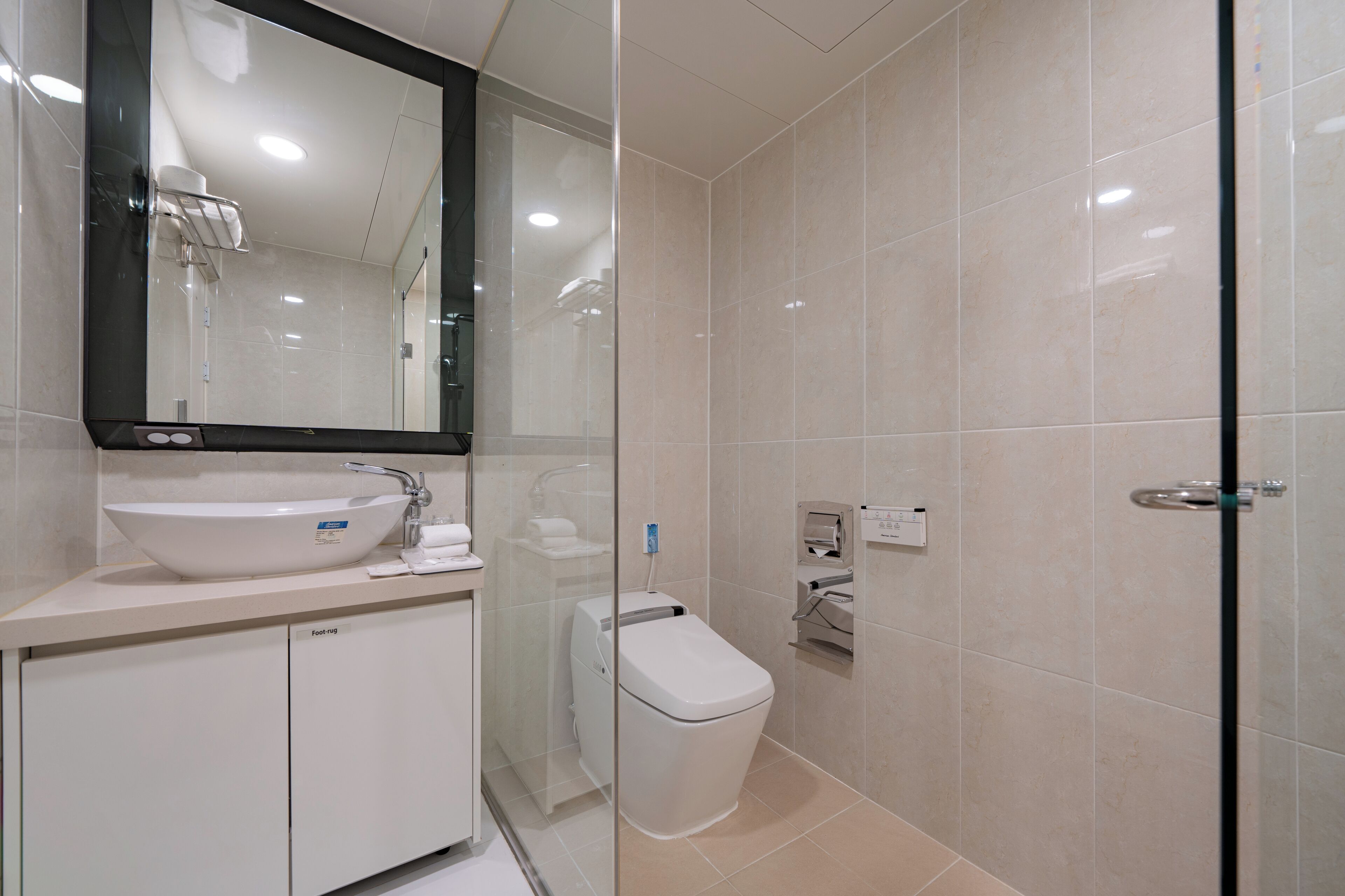 Un baño moderno con lavamanos, espejo y retrete blancos.