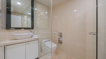 A modern bathroom with a large mirror, a sink, a toilet, and a glass shower enclosure.