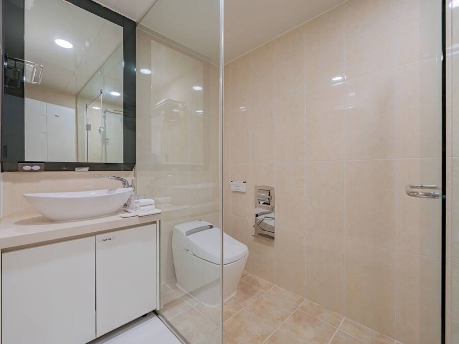 A modern bathroom with a large mirror, a sink, a toilet, and a glass shower enclosure.