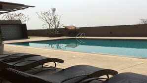 A swimming pool with lounge chairs, a ladder, and a small garden area. - Himawari at Condo (Khon Kaen)