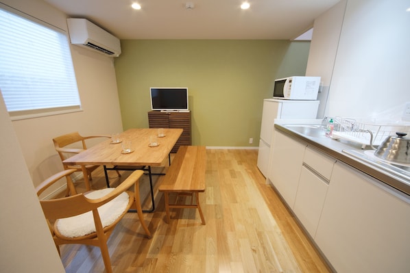 A compact kitchen with a dining table, chairs, a microwave, and a sink.