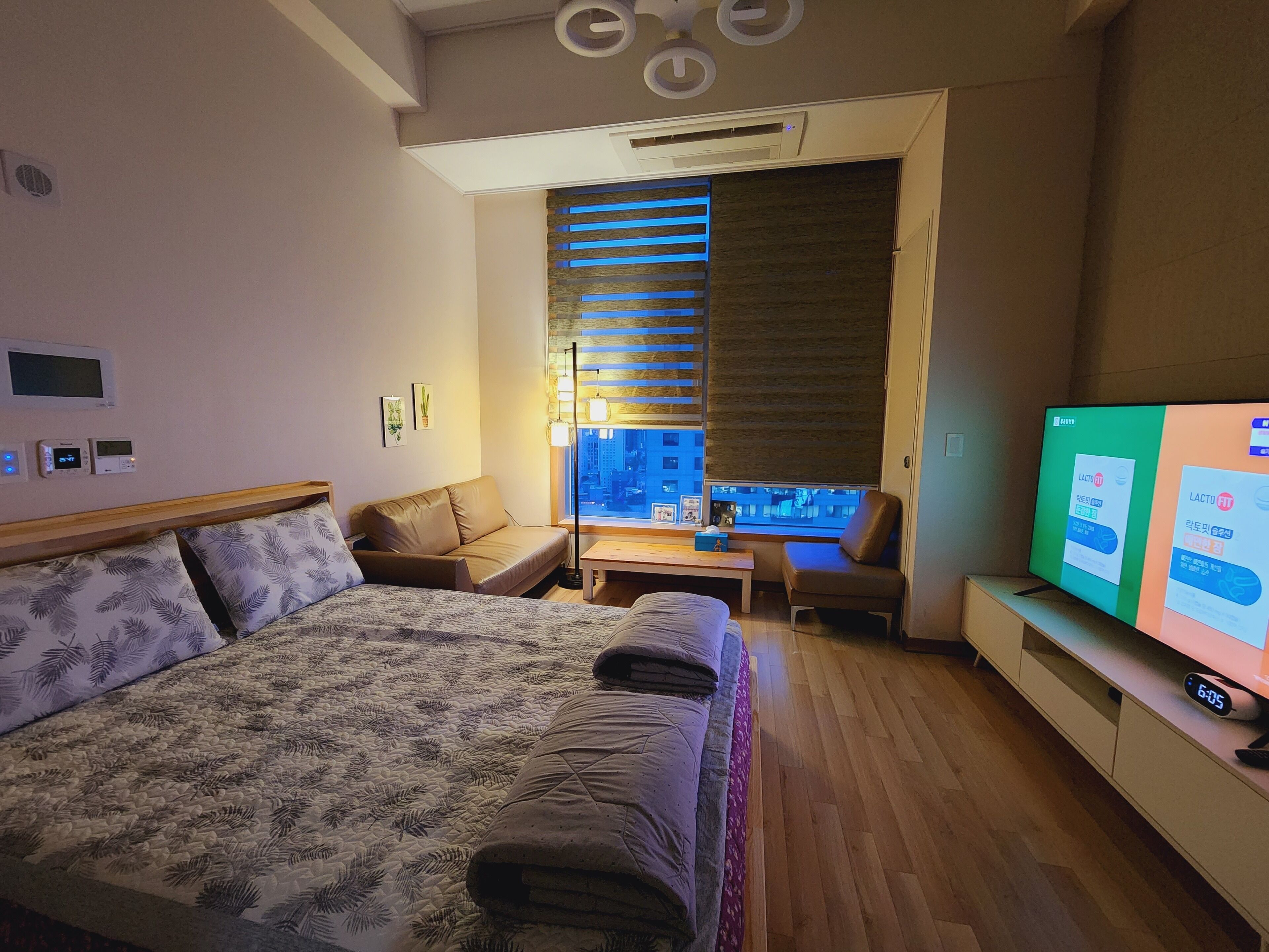Una habitación de hotel moderna con una cama grande, un sofá, una mesita y un televisor.
