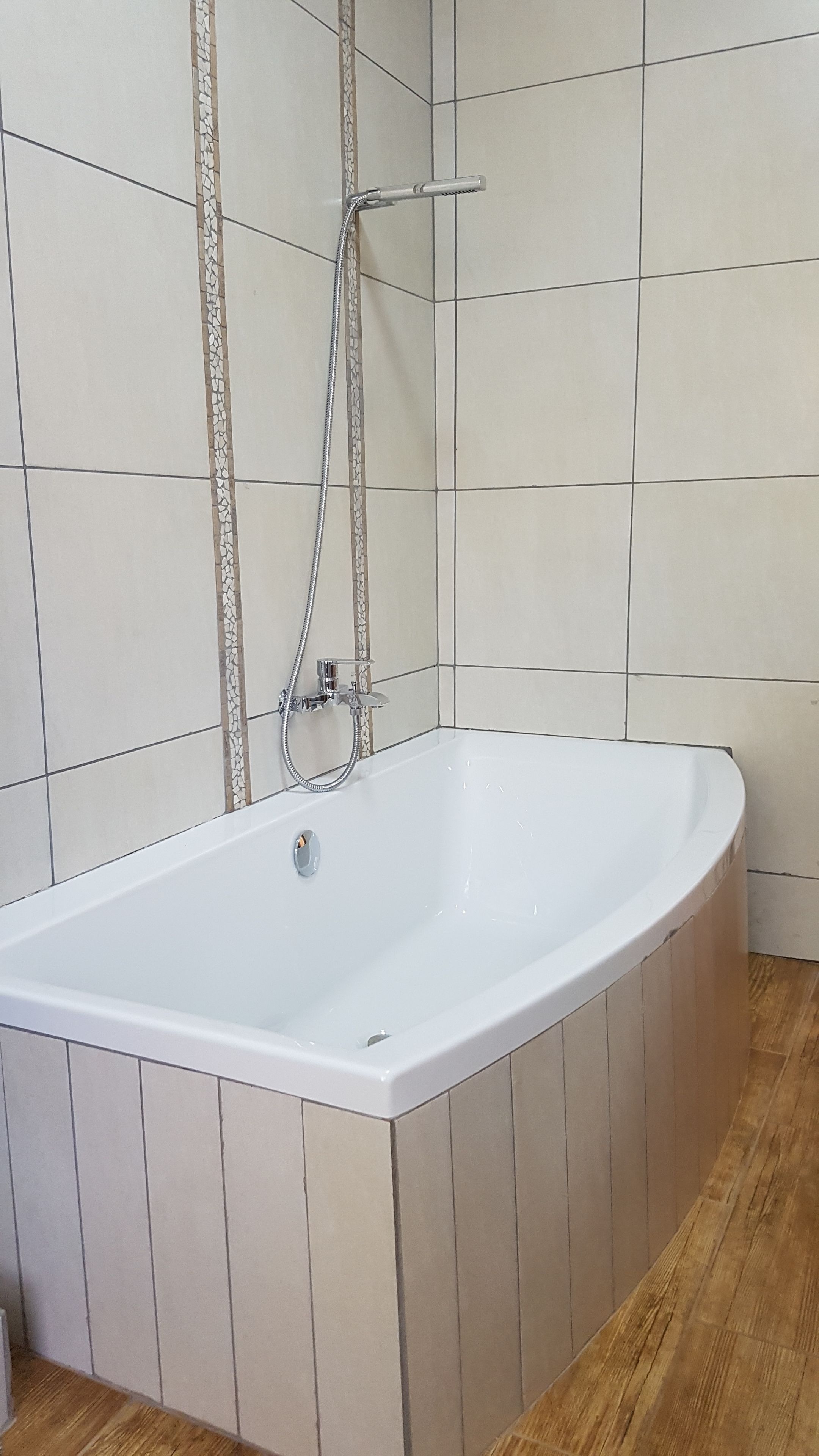 Une salle de bain avec une baignoire, une douche et un sol carrelé.