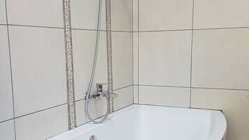 Une salle de bain avec une baignoire, une douche et un sol carrelé.