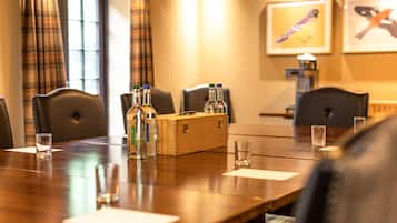 A conference room with a wooden table, chairs, bottles, glasses, and a wooden box.