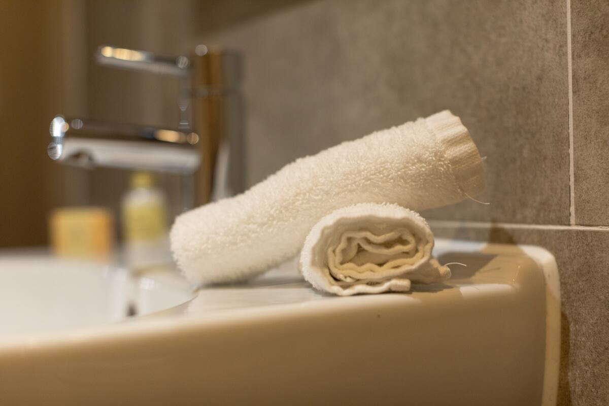 A bathroom with a white towel, a sink, and a faucet.