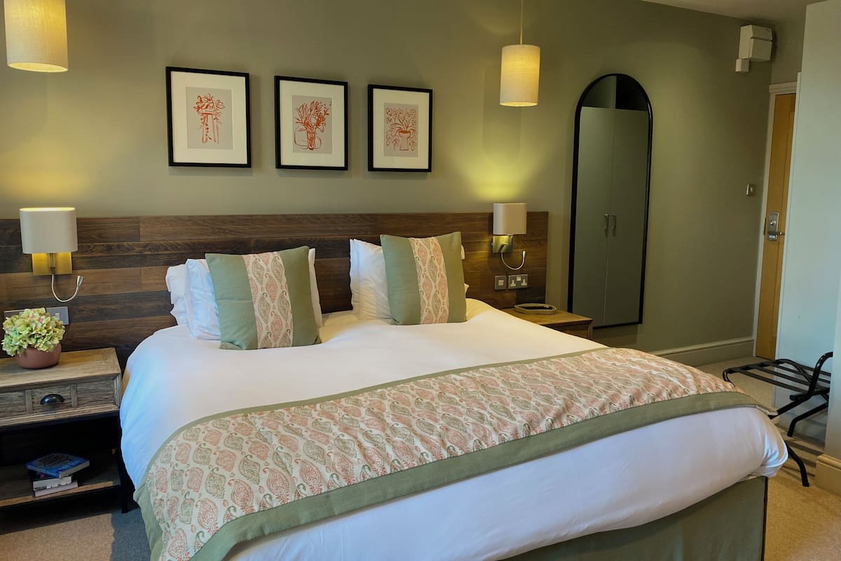 A neatly made bed with patterned bedding, a bedside table with a lamp, and framed artwork on the wall.