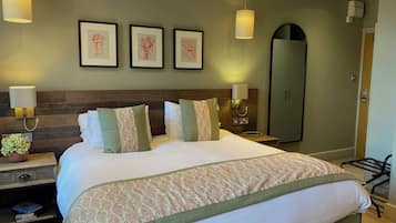 A neatly made bed with patterned bedding, a bedside table with a lamp, and framed artwork on the wall.