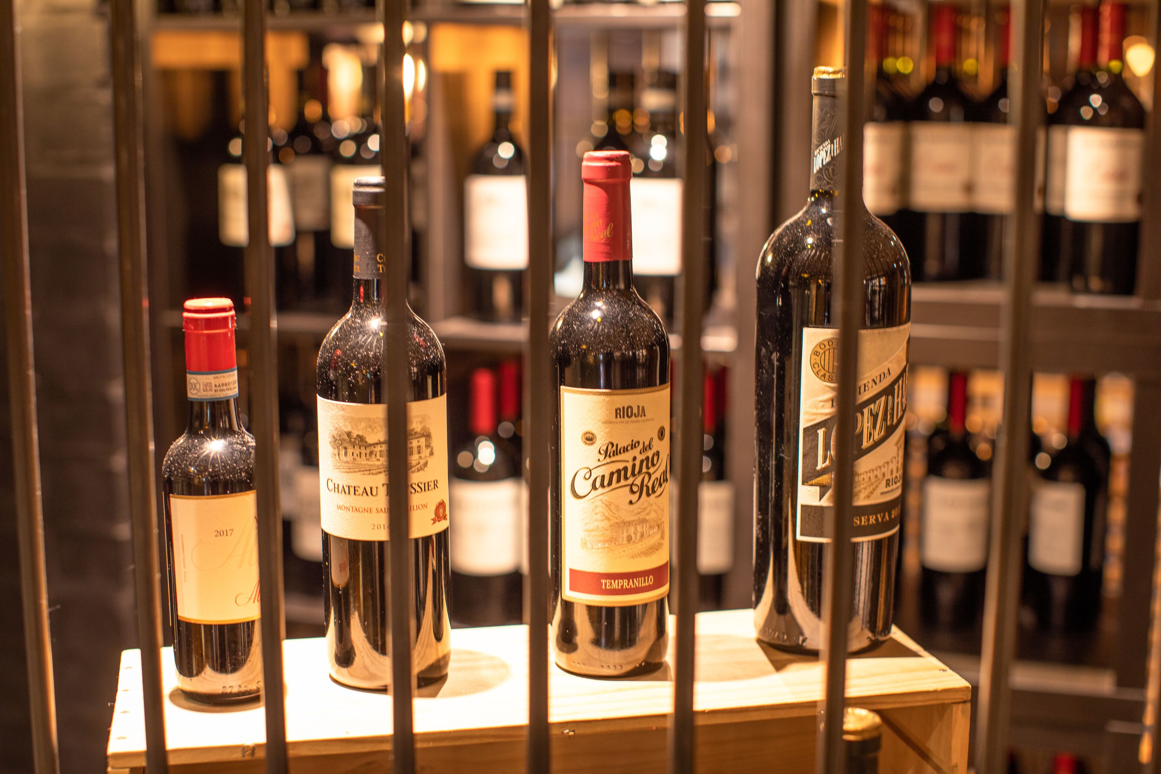 Varias botellas de vino exhibidas en un espacio bien iluminado y ordenado, probablemente en una tienda de vinos o sala de degustación.