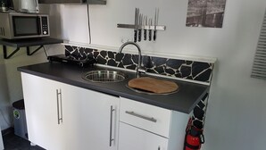 A compact kitchen with a microwave, sink, and knife set on the wall. - Zimmervermietung Wesermarsch (Berne)