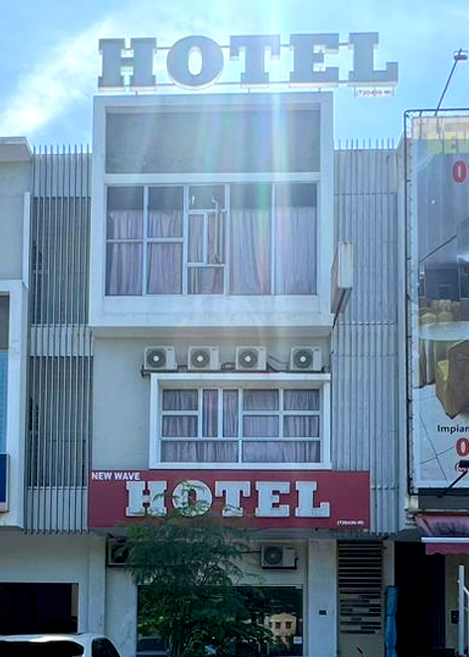 A hotel with a prominent 'HOTEL' sign, multiple windows, and air conditioning units.