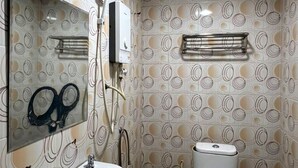 Un baño con inodoro, lavamanos y ducha. Las paredes tienen un diseño circular y hay un espejo sobre el lavamanos.