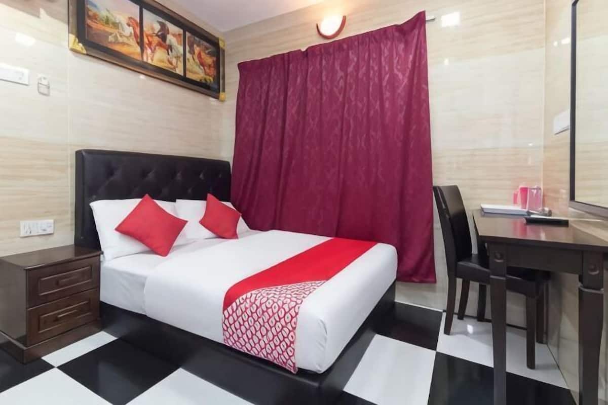 Une chambre d’hôtel avec un lit, un bureau, une chaise et une fenêtre avec des rideaux.