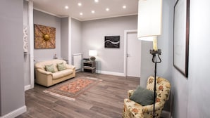 Een moderne woonkamer met een beige bank, een fauteuil met bloemenprint, een tapijt met patroon en een vloerlamp.