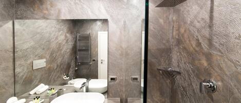 A modern bathroom with a large mirror, a white sink, a shower, and a towel rack.