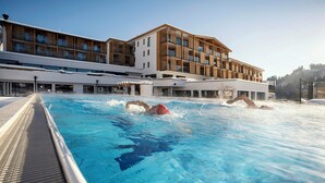 A swimming pool with a wooden deck and a modern building in the background.